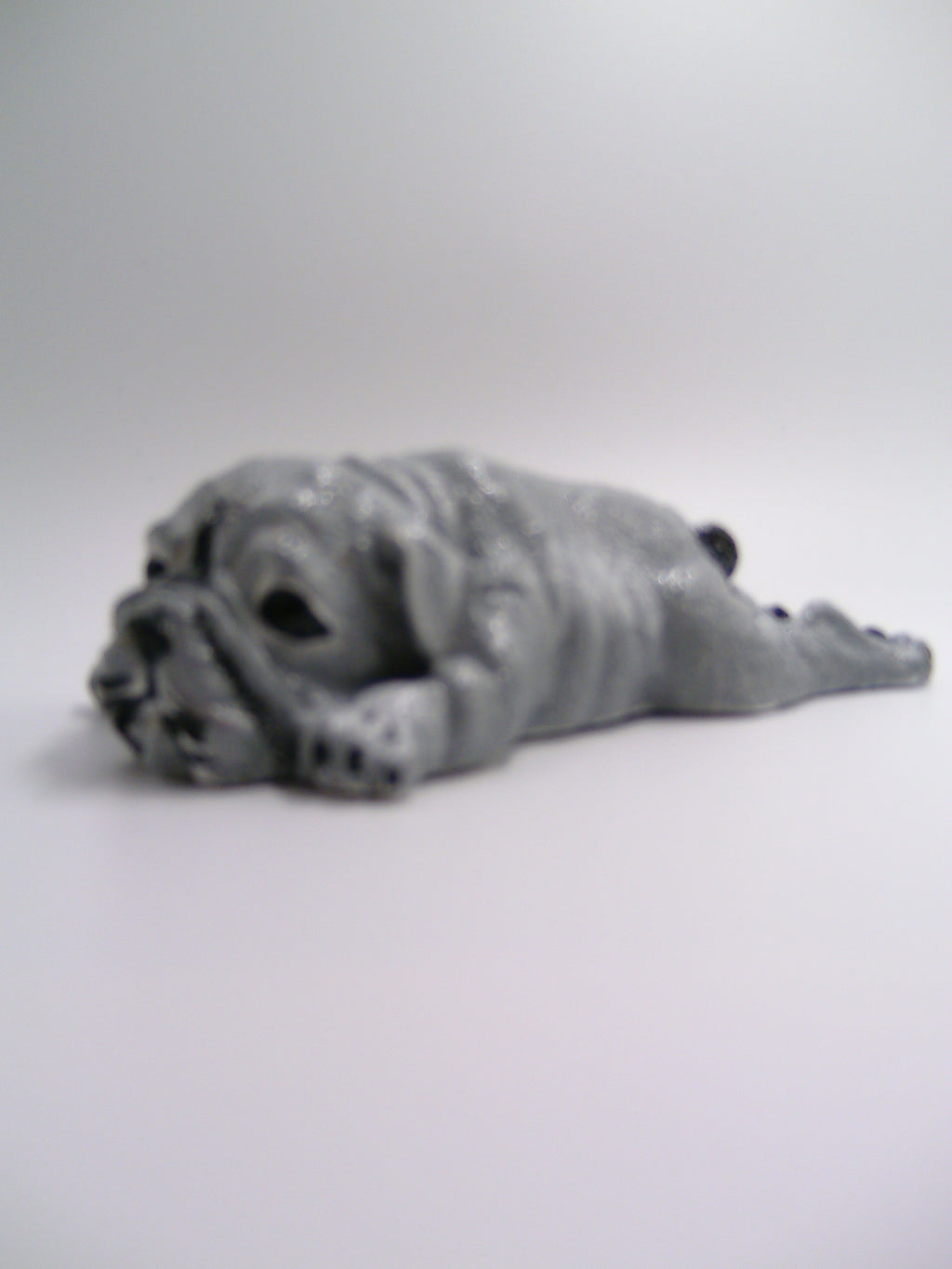 Bulldoggen-Figur aus Gips – liegend mit ausgestreckten Pfoten